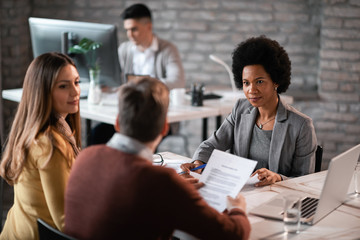 Wall Mural - Black female bank manager talking to a couple about their loan application on a meeting.