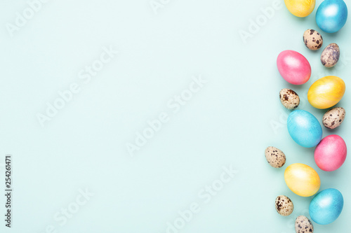 Border made of colorful Easter eggs on turquoise background. Top view, copy s...