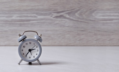 A small alarm clock shows the time, stands on a light background.