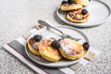 Wall Mural - Homemade curd fritters with berries and a cup of milk on a gray background. Healthy and diet breakfast