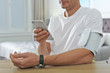 © New Africa - Man checking blood pressure with modern monitor and smartphone at table indoors, closeup. Cardiology concept