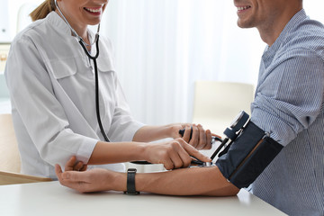 Wall Mural - Doctor checking patient's blood pressure in hospital, closeup. Cardiology concept