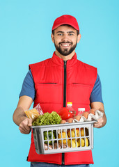 Canvas Print - Man holding basket with fresh products on color background. Food delivery service