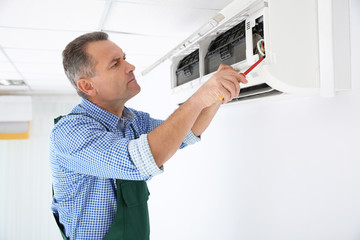 Poster - Electrician with screwdriver repairing air conditioner indoors