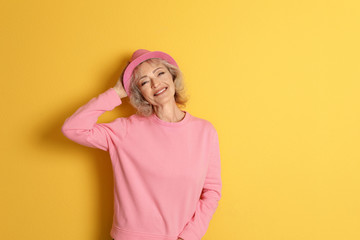 Wall Mural - Portrait of mature woman in hipster outfit on color background. Space for text