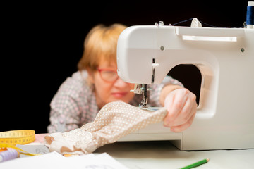 woman in glasses using sewing machine or threading on dark background b