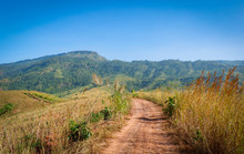 Dirt Road On Field To Hill Mountain - Rural Dusty Countryside Road For Off Road Pickup Truck