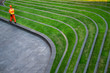 © mrwinn - A security person in orange suit walking around a green grass garden with architectural leading line.