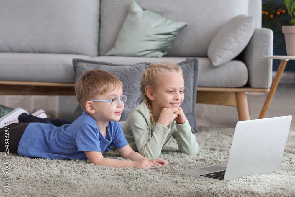 Cute little children watching cartoons at home
