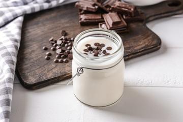 Jar with tasty yogurt and chocolate chips on white table