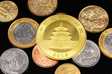 A Macro Image Of Miscellaneous Brazilian Coins With A Chinese One Ounce Gold Panda Coin On A Black Reflective Background Close Up 