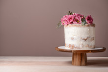 Sweet Cake With Floral Decor On Table Against Color Background
