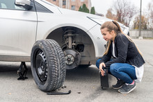 Woman In Despair Looking At Spare Wheel For Car