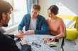 © estradaanton - Couple buy or rent apartment together. Business deal. Young man put signature on documents and look at realtor. He point on document.