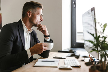 Wall Mural - image of european businessman drinking coffee while working on computer in office