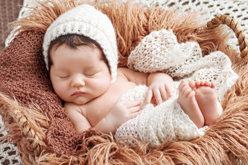 beautiful little newborn baby 2 weeks sleeping in a basket with knitted plaid. portrait of pretty ne