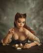 © kharchenkoirina - Fantasy woman cat. redhead lady with cat ears made of hair eats white mouse from golden dishes. pussycat eats cute animals. sexy lady in vintage dress, creative work of makeup artist and hairdresser