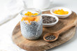 Chia pudding in glass jar with almond milk and mango on white background