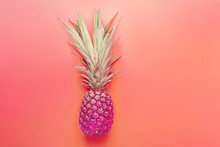 Bright Purple Neon Color Pineapple On Gradient Pink Coral Background. Long Bushy Green Leaves. Summer Vacation Travel Tropical Fruits Fun Fashion Concept. Beach Pool Party Invitation