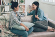 © PR Image Factory - Two laughing asian female friends talking in living room at home sitting relaxing on couch. girls chatting about life and relations gossip and slumber party concept. women roommates having fun sofa