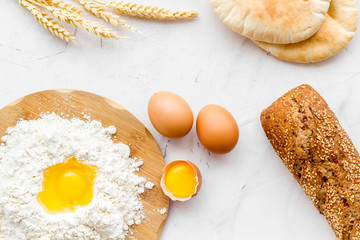 Make bread concept. Bread near wheat ears, flour and eggs on white background top view