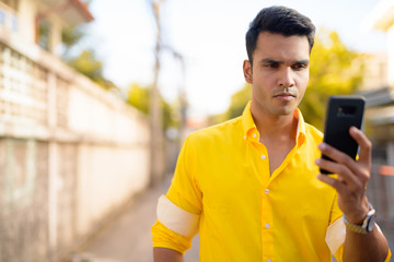 Young handsome Indian man using phone in the streets outdoors