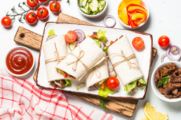 Wall Mural - Burritos tortilla wraps with beef and vegetables on white.