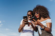 © karrastock - Two happy friends using the mobile in the street. Friendship concept.
