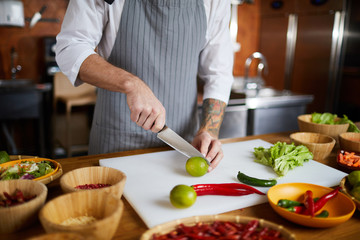 Wall Mural - Mid section portrait of unrecognizable chef cutting vegetables while cooking spicy dish in restaurant, copy space