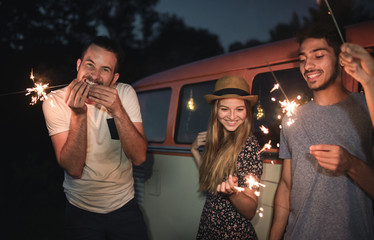 Wall Mural - A group of friends with sparklers standing outdoors at dusk.