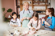 © Seventyfour - Portrait of smiling woman working with children in pottery class