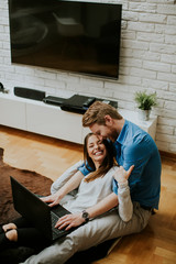 Wall Mural - Close up of a couple using a notebook while sitting on the floor in their living room