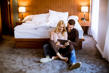 Wall Mural - Young happy couple in love sitting on floor resting and  having fun surfing internet