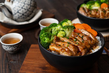 Japanese Food Style : Top View Of Homemade Chicken Teriyaki Grilled With Rice , Carrot , Broccoli Put On The Black Bowl And Place On Wooden Table
