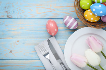 Kitchen cutlery with easter eggs and tulip flowers on wooden table