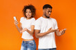 © Prostock-studio - Disappointed black millennial man and woman looking at smartphones
