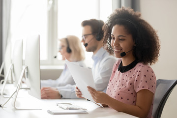 Sticker - Smiling african woman call center operator wearing headset reading papers