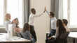 © fizkes - Happy diverse employees giving high five together celebrating shared win