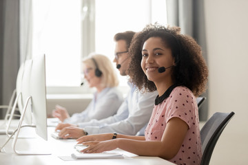 Wall Mural - happy african call center operator wearing headset looking at camera