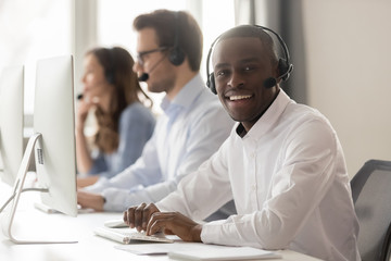 Wall Mural - happy african call center agent in headset posing at workplace