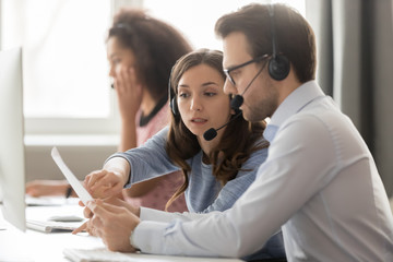 Wall Mural - call center agents in headsets discussing papers helping at workplace