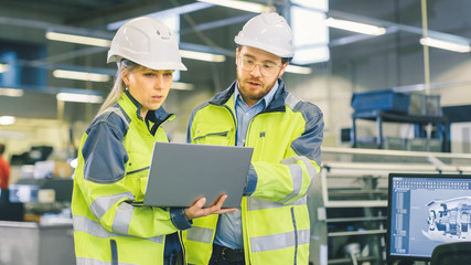 Poster - Male Industrial Worker and Female Chief Mechanical Engineer in Walk Through Manufacturing Plant while Discuss Factory's New Project and Using Laptop. Facility Has Working Machinery.