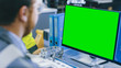 © Gorodenkoff - Close-up Back View of the Mechanical Engineer Working on Personal Computer with Green Screen Mock up GReat for Template. Professional Working At the Factory.