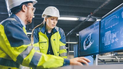 Fototapete - At the Factory: Male Mechanical Engineer and Female Chief Engineer Work Together on the Personal Computer, They Discuss Details of the 3D Engine Model Design.