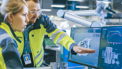 Fototapete - At the Factory: Male Mechanical Engineer and Female Chief Engineer Work Together on the Personal Computer, They Discuss Details of the 3D Engine Model for Robotic Arm.