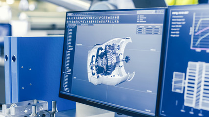 Poster - Close-up Shot of the 3D CAD Model of the Engine Shown on Computer Screen. In the Background Manufacturing Factory with People Working.