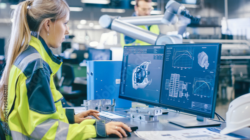 Fotomural At the Factory: Female Mechanical Engineer Designs 3D Engine on Her Personal Computer, Male Automation Engineer Uses Laptop for Programming Robotic Arm