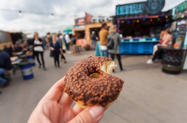 Tasty donut in hand of visitor of the street food market of Copenhagen, Denmark. Leisure in Scandinavia with drinks and food of popular city area