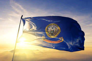 Poster - Idaho state of United States flag waving on the top sunrise mist fog