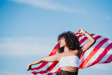 Black woman with afro hair and an american flag celebrating the independence day of USA